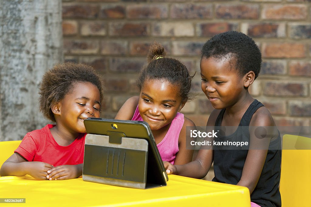 Three african kids playing together on tablet. Portrait of three african girls playing leisure games on tablet. Africa Stock Photo