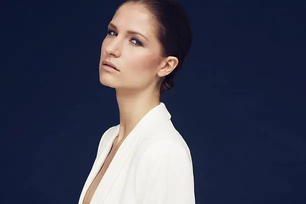 fashionshoot of a model in white jacket against blue background