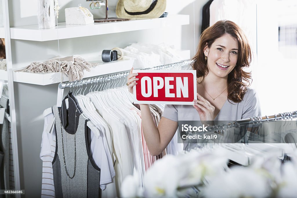 Boutique, open for business Young woman (20s) in clothing store, with OPEN sign. 20-29 Years Stock Photo