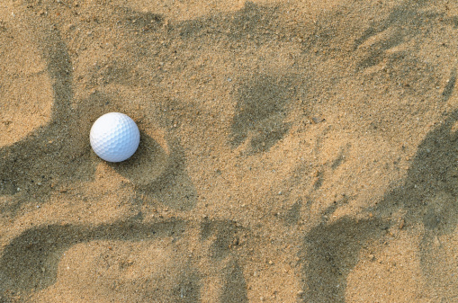 A golf ball on the sand ; top view