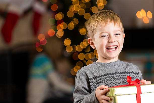 podekscytowany młody chłopiec trzyma prezent na boże narodzenie - giving christmas lifestyles holiday zdjęcia i obrazy z banku zdjęć