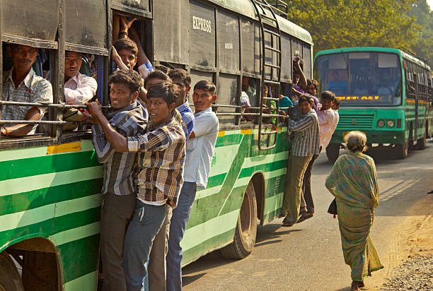 Tiruvannamalai, India - February 5, 2014: Crowded bus with people hanging outside is a common sight in India, especially during rush hours. Though dangerous many young people run the risk in stead of waiting for the next bus which may also be overcrowded.