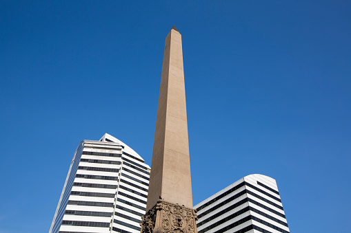Plaza Francia in Altamira disctrict in Caracas. Obelisk in between two modern white buildings against a blue sky. Venezuela 2015