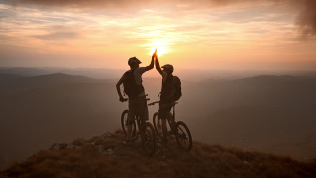 Aerial of mountain bikers on the top at sunset