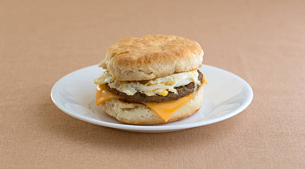 uova e salsiccia e formaggio biscotto sulla piastra - breakfast eggs fried egg sausage foto e immagini stock