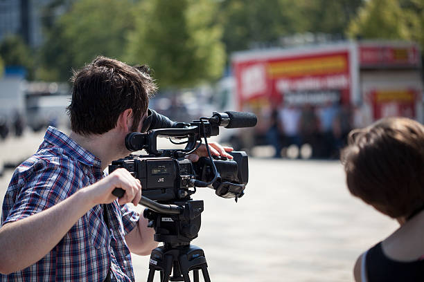 Film team Wiesbaden, Germany - July 27, 2012: Film-recording team at demonstration against a speech of Neonazis in the city center of Wiesbaden. In the background the pre-election party of German NPD (Nationaldemokratische Partei Deutschlands). Selective focus national democratic party of germany stock pictures, royalty-free photos & images