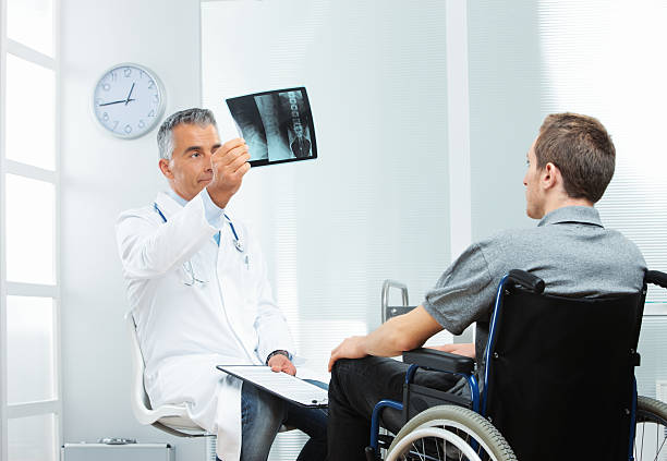 Disabled young man at doctor office Young patient with mature doctor discussing x-ray invalid person stock pictures, royalty-free photos & images