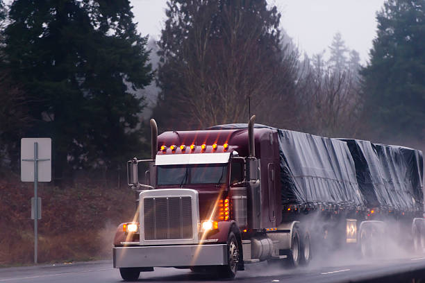 istock Big burgundy rig in rain on high way 482397847