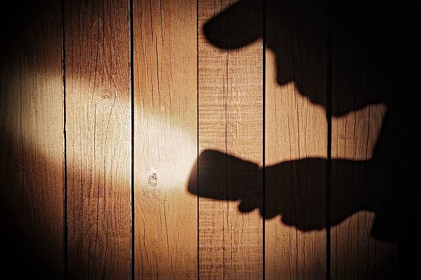 istock Human silhouette with flashlight in shadow on wood background, X 482398651