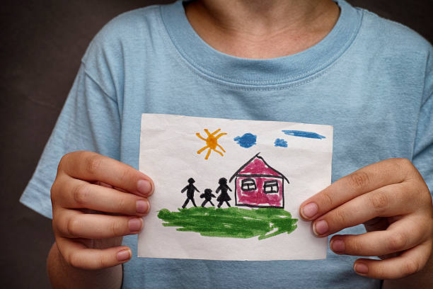 istock Child holds a drawn house with family 482398996