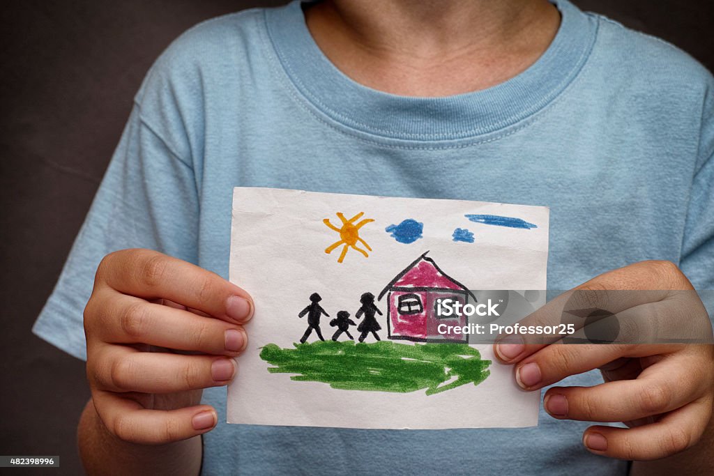 Child holds a drawn house with family Child holds a drawn house with family. Close up. Child's Drawing Stock Photo