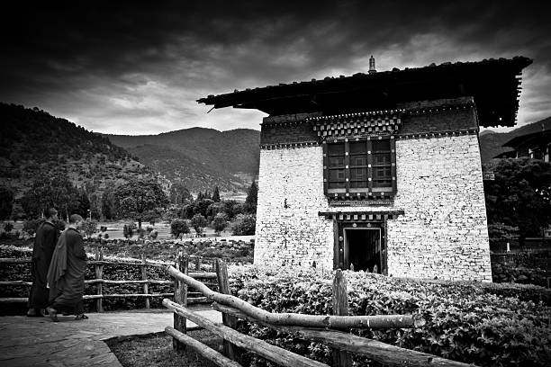 Two Buddhist monks of The Punakha Fortress Monastery, Paro, Bhutan Paro, Bhutan - October 26, 2014: Two Buddhist monks arrive at the gatehouse of The Punakha Fortress Monastery, Paro, Bhutan black and white travel travel destinations monk stock pictures, royalty-free photos & images