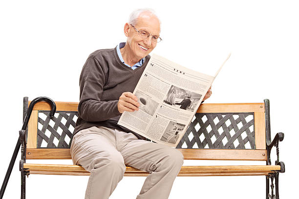 istock Senior reading a newspaper seated on a bench 482404272