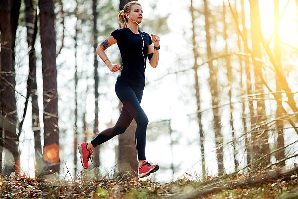 istock young women running through the forest 482404365