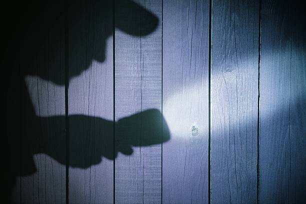 istock Human silhouette with flashlight in shadow on wood background, X 482405391