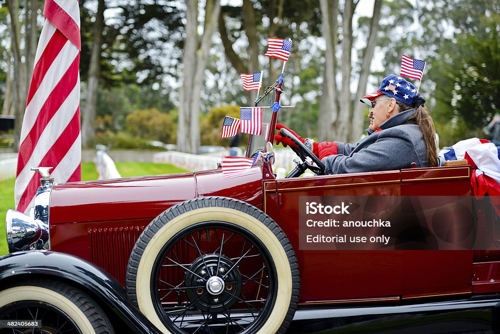 US Memorial Day Ceremony, The Presidio Cemetery,San Francisco San Francisco, USA  - May 27, 2013: US Memorial Day Ceremony at the San Francisco National Cemetery, The Presidio. Red Old car is parked on a cemetery. Senior Couple sitting in the car decorated by many American Flags. Couple - Relationship Stock Photo