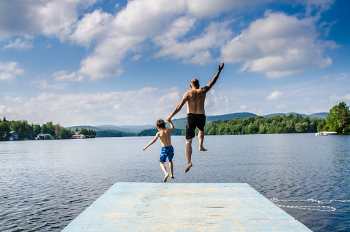 Father and son jumping in lake Sept-Iles (Portneuf) from the dock