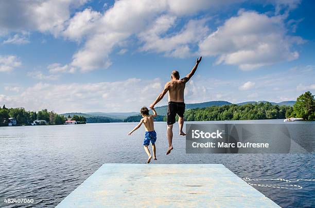 Father And Son Jumping In Lake Stock Photo - Download Image Now - Jumping, Lake, Summer