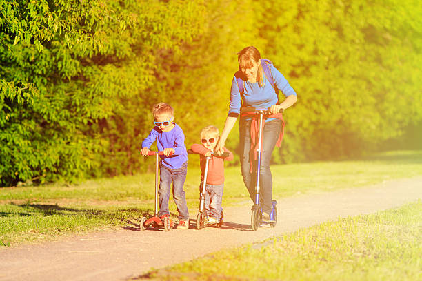 istock mother with kids riding scooters in summer 482408390