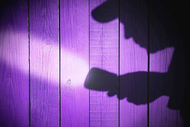 istock Human silhouette with flashlight in shadow on wood background, X 482408719