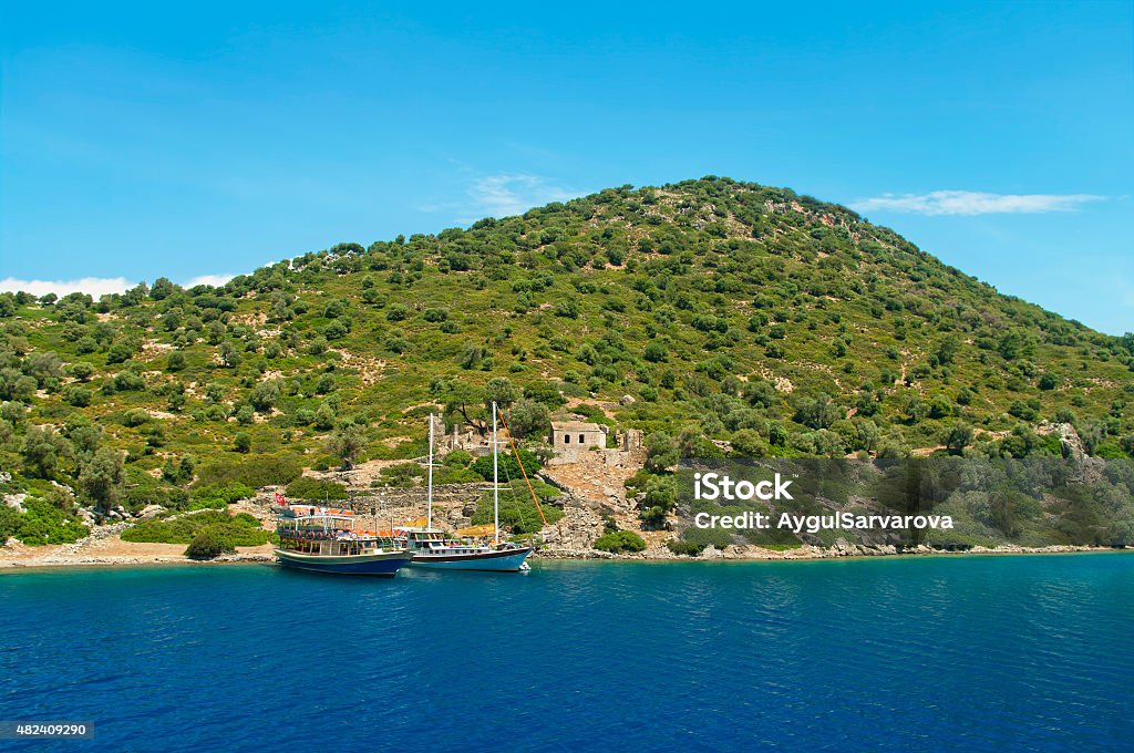 two boats moored at green island with ancient ruins two tourist boats moored at green Camellia island with ruins of 12th century byzantine church in Aegean sea, Turkey 2015 Stock Photo