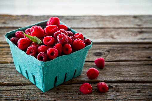 Handpicked organic raspberries in a blue-green basket, fresh from the farmer's market