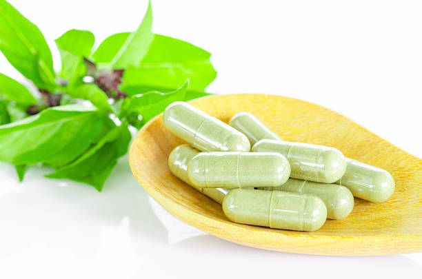 istock Green Herb capsule on wooden spoon and leaf. 482413166