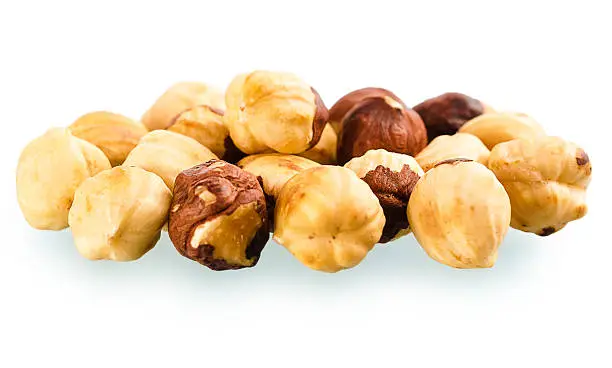 Photo of pile of shell-less hazelnuts, isolated on white background