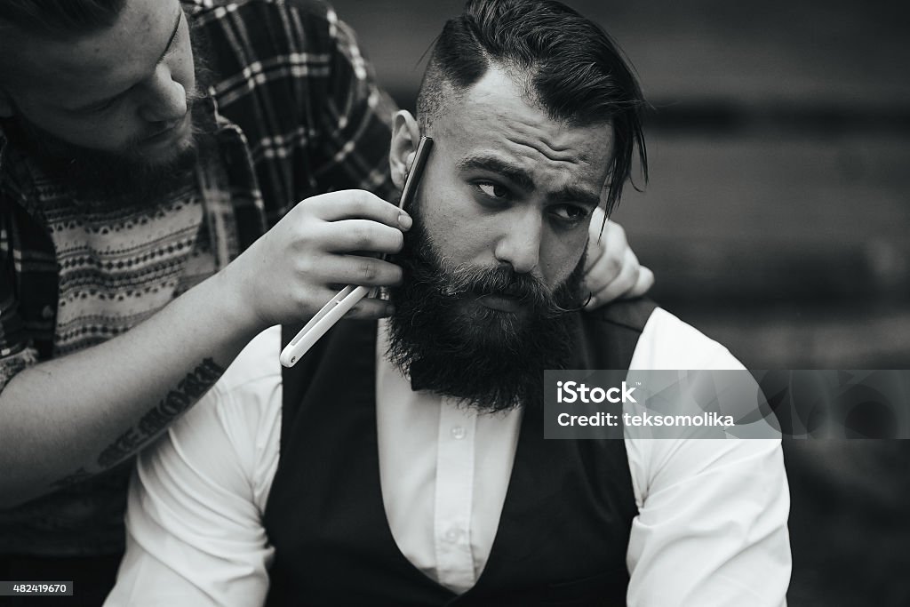 barber shaves a bearded man barber shaves a bearded man in vintage atmosphere Barber Stock Photo