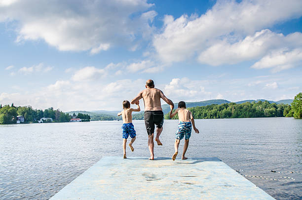 istock Father and sons jumping in lake 482424050