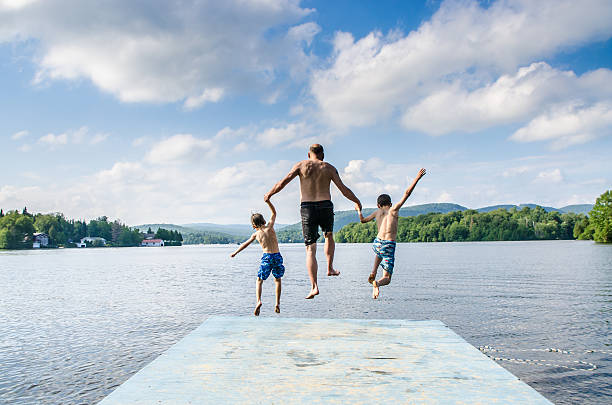 istock Father and sons jumping in lake 482424062