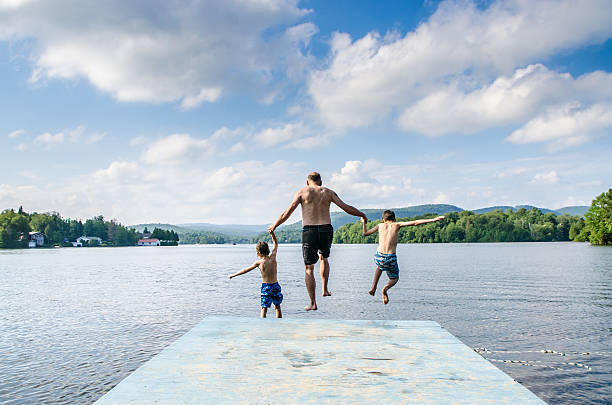 istock Father and sons jumping in lake 482424066