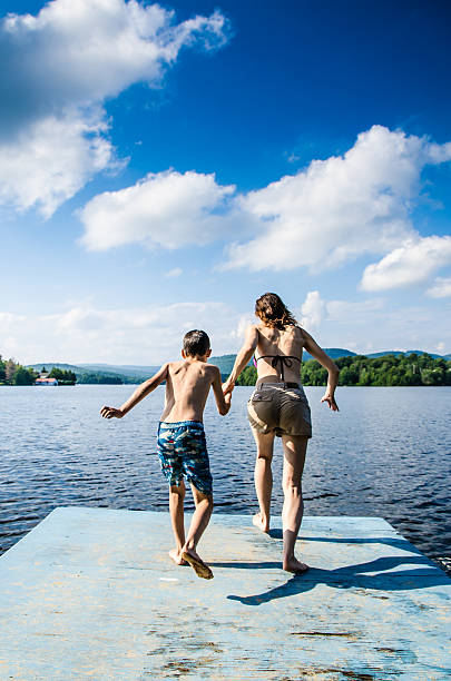istock Mother and son jumping in lake from dock 482424072