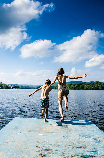 istock Mother and son jumping in lake from dock 482424076