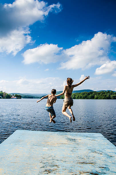 istock Mother and son jumping in lake from dock 482424092