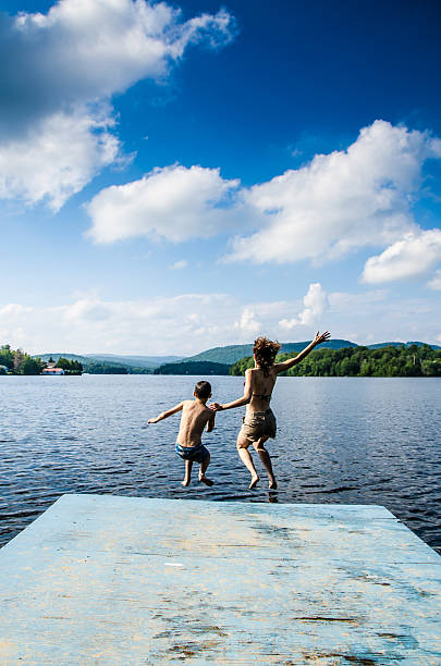 istock Mother and son jumping in lake from dock 482424098
