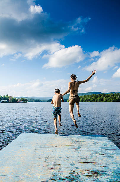istock Mother and son jumping in lake from dock 482424110