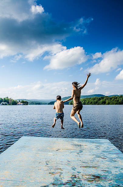 istock Mother and son jumping in lake from dock 482424114