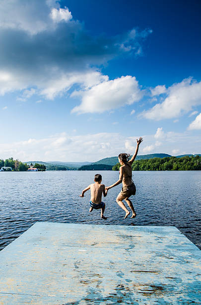 istock Mother and son jumping in lake from dock 482424122