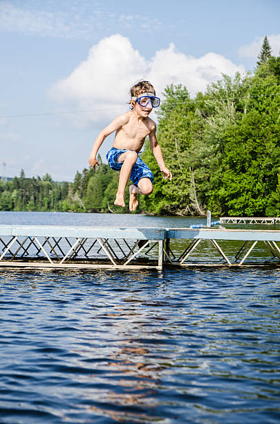 istock Boy jumping in lake from dock 482424484