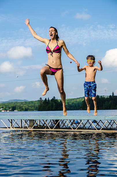istock Mother and son jumping in lake from dock 482424506