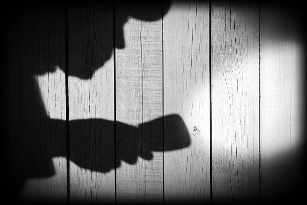 istock Unrecognizable burglar with  flashlight  in shadow on wood backg 482431983