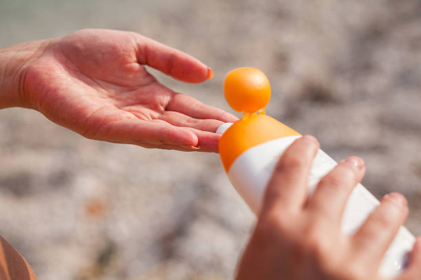 istock Girl standing on the beach and using suncream. 482433614