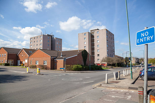 council housing 60s tower blocks Potter Street Harlow Essex council housing 60s tower blocks Harlow Essex - in the suburb of Potter Street, a view of a mini-roundabout in front of the Village Hall and main through road with 'NO ENTRY' sign harlow essex stock pictures, royalty-free photos & images