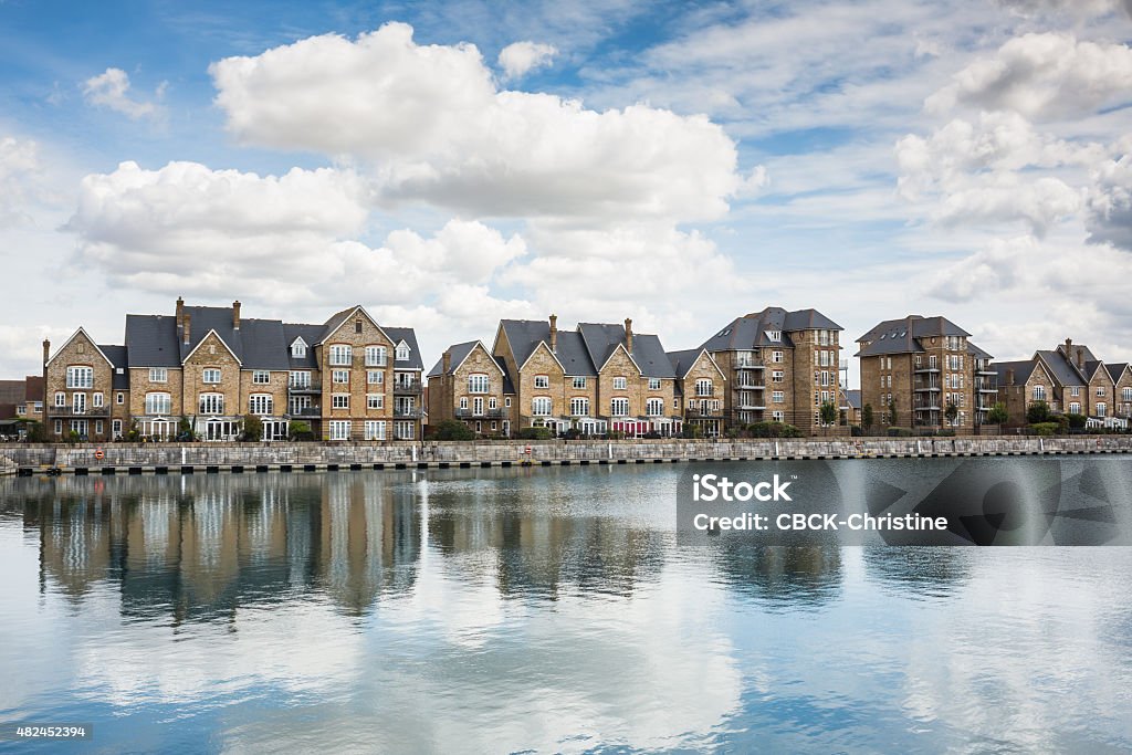 Terrrace houses by a marine dock. Reflections in the water of a cloudscape and a row of terrace houses on the side of a marine dock in the docklands area of St Mary's Island, Chatham, Kent. Chatham - England Stock Photo
