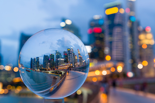 Reflection of Jubilee Bridge and Central Business District of Singapore during dusk hour in a glass ball, tourists enjoy the night scene at Jubilee Bridge.