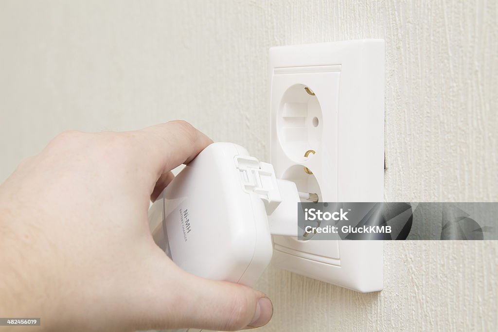 insert charger into wall outlet Adult Stock Photo