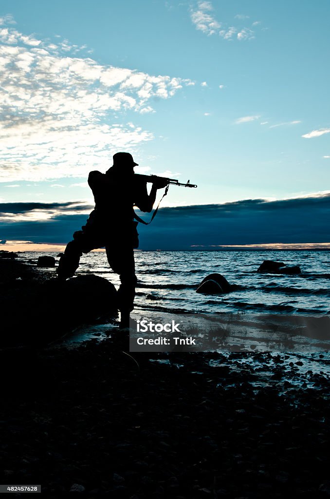 military silhouette at sunset military water, rocky shore 2015 Stock Photo