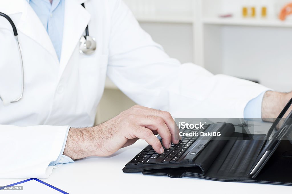 Doctor with Digital Tablet Close-up of doctors hands working on a Digital Tablet. Adult Stock Photo