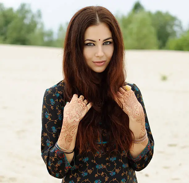 beautiful woman in oriental indian style with mehendi with and red hair